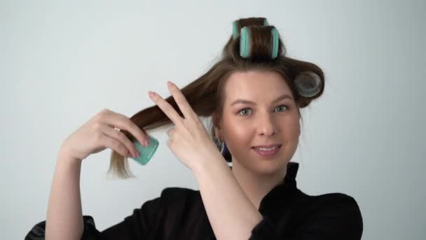 Fille en utilisant curler sur les cheveux, fait coiffure. Jeune femme en sous-vêtements peignoir . — Video