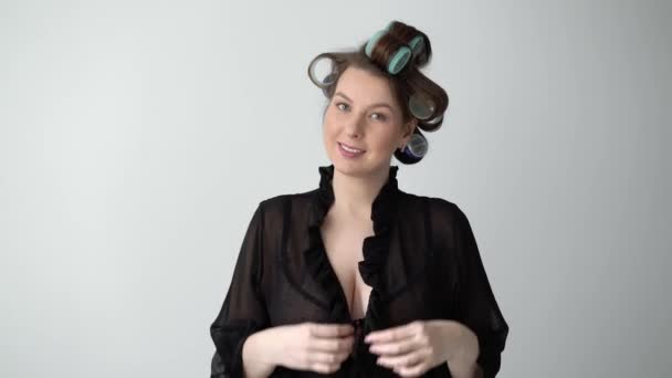 Girl with curlers rollers on hair. Young woman in black sexy bathrobe underwear. — Stock Video