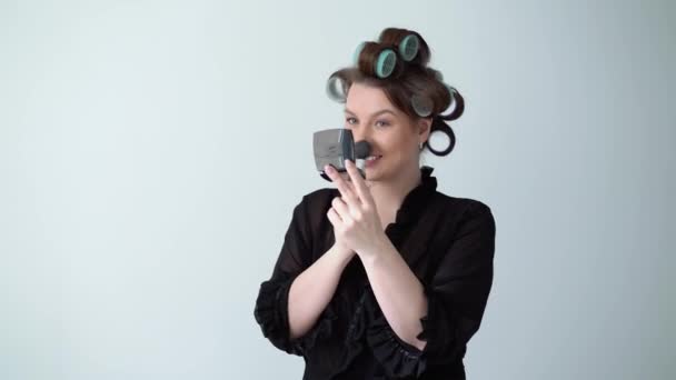 Mujer joven en rulos rodillos en el pelo haciendo maquillaje con cepillo, Hermosa chica — Vídeos de Stock