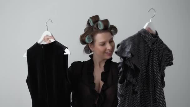 Femeie tânără în curlere pe păr și lenjerie alegând rochia de purtat din garderobă — Videoclip de stoc