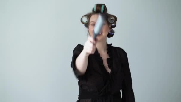 Woman with curlers rollers on hair and in bathrobe dancing singing in hairbrush. — Stock Video