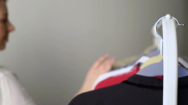 Genç bir kadın elbise seçiyor ve ne giyeceğini arıyor. Depo ya da gardırop