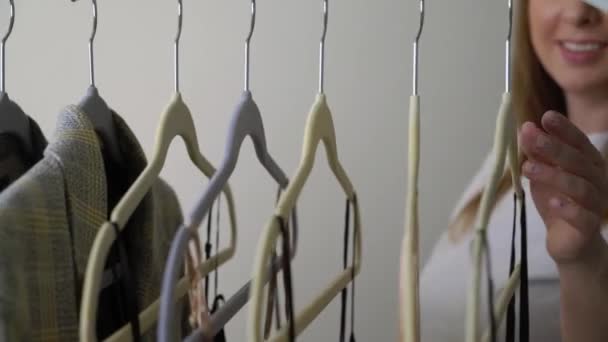 Young woman choosing clothes on a rack searching what to wear. Store or wardrobe — Stock Video