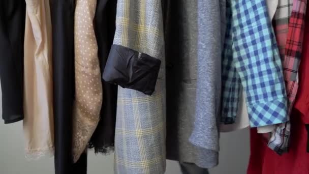 Young woman choosing clothes on a rack searching what to wear. Store or wardrobe — Stock Video