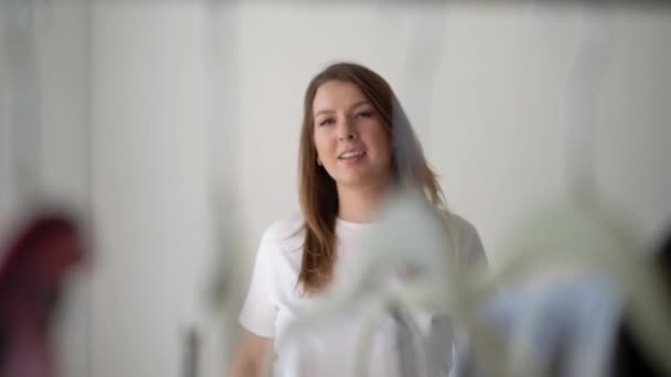 Jonge vrouw uitkleden kiezen van kleding op een rek op zoek naar wat te dragen — Stockvideo