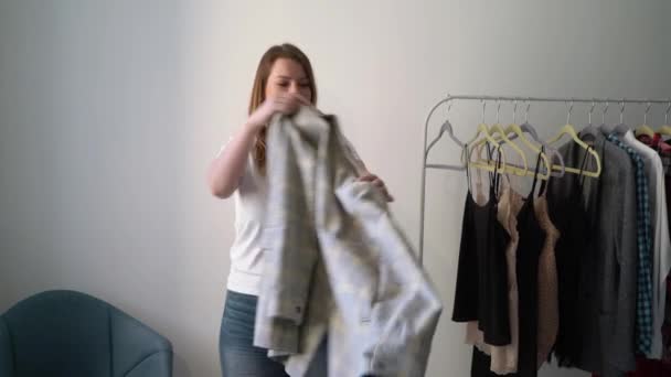 Young woman choosing clothes on a rack searching what to wear. Store or wardrobe — Stock Video