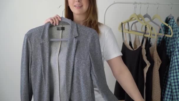 Jeune femme qui choisit des vêtements sur un étagère à la recherche de quoi porter. Magasin ou garde-robe — Video