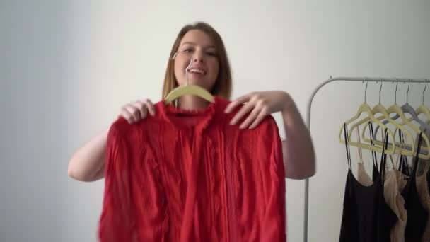 Ung kvinde vælger tøj på en rack søger hvad de skal bære. Opbevaring eller garderobe – Stock-video