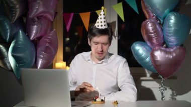 Genç adam doğum gününü yalnız kutluyor. Dizüstü bilgisayar web kamerası kullanılıyor