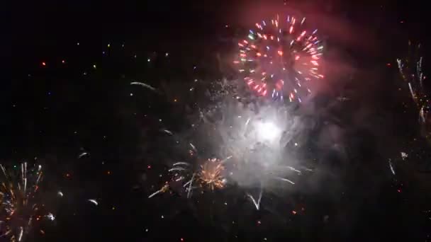 Fuegos artificiales coloridos que explotan y llenan la oscuridad del cielo nocturno con luz de colores — Vídeos de Stock