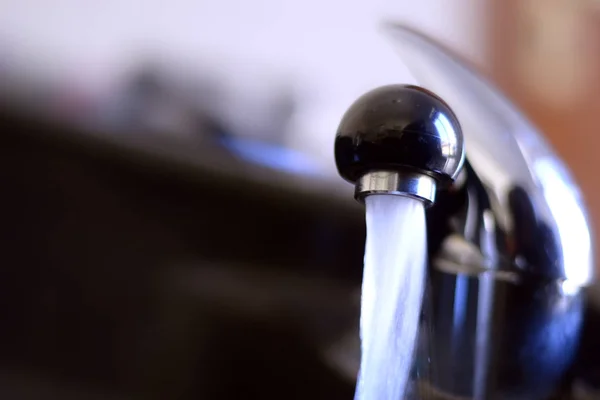 Drinking water from the tap in the sink.