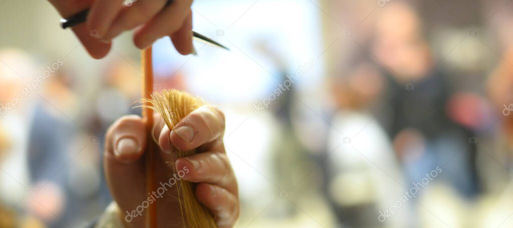 Hairdresser with a lock of hair between her fingers ready to cut