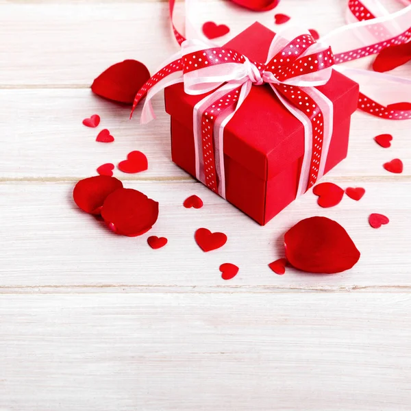 Valentinshintergrund der Geschenkbox und Rosenblätter auf weißem Holz. — Stockfoto