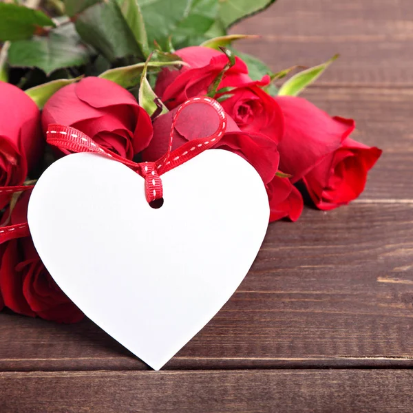 Valentinstag Hintergrund der weißen Geschenkanhänger und roten Rosen auf Holz. s lizenzfreie Stockfotos
