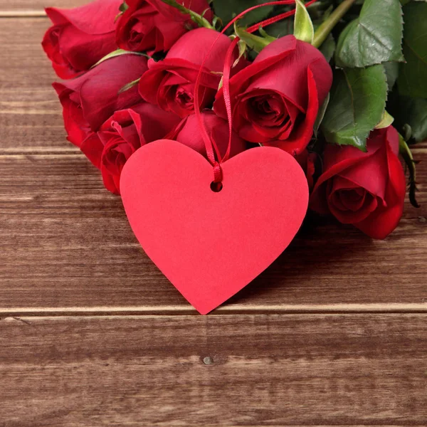 Valentinshintergrund aus Geschenkanhänger und roten Rosen auf Holz. Raum für Stockbild