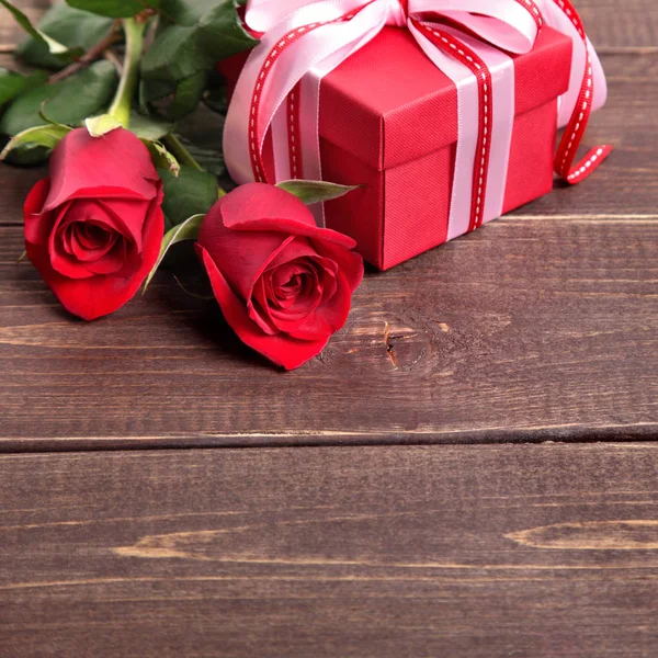 Valentine background of gift box and red roses on wood. Space fo Royalty Free Stock Photos