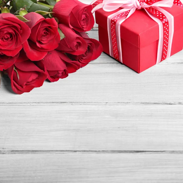 Valentine background of gift box and red roses on white wood. Sp Stock Image
