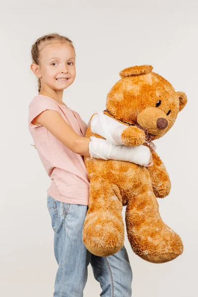 Smiling girl with broken arm is looking at the camera — Stock Photo, Image