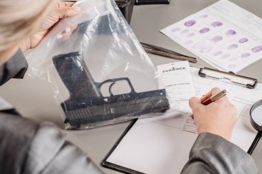 Detective through a magnifying glass looking at a evidence  clipart