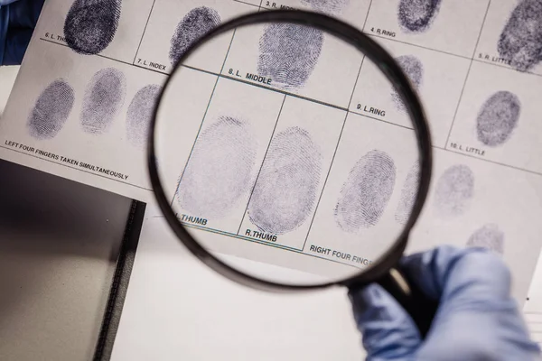 Детектив через увеличительное стекло смотрит на отпечатки пальцев — стоковое фото