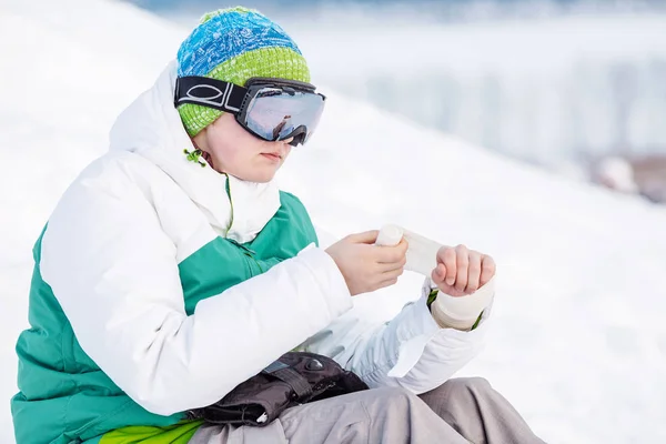 若い男は 雪の上に座って 弾性包帯 — ストック写真