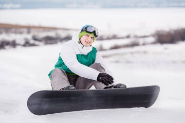 Snowboard Kar yamaç üzerinde oturuyor. insanlar ve sağlıklı yaşam konsepti