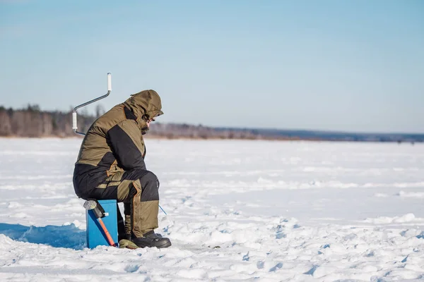 Winter fishing on lake. Ice drill and ice fishing rod on frozen lake.