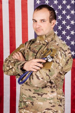 bir stetoskop ile askeri doktor. Adam geçti silah ile kamuflaj giyiyor.