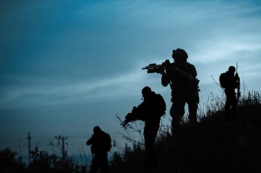 Silhouette of military soldiers with weapons at night clipart