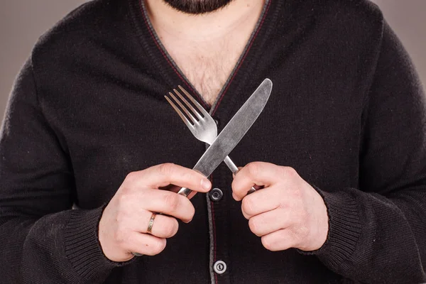 hungry man holding cutlery fork and knife on hand. diet, food, healthy, style concept. isolated on a gray studio background.