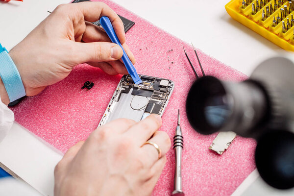 Close up hands of a service worker repairing modern smarphone. 