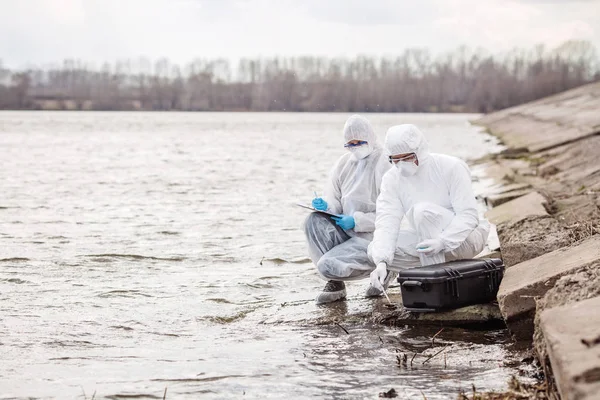 Cientistas ou biólogos vestindo uniformes de proteção trabalhando juntos na análise de água . — Fotografia de Stock
