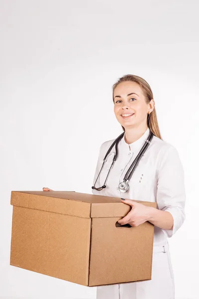 Arzt lächelt, hält Schachtel in der Hand und blickt in Kamera. — Stockfoto