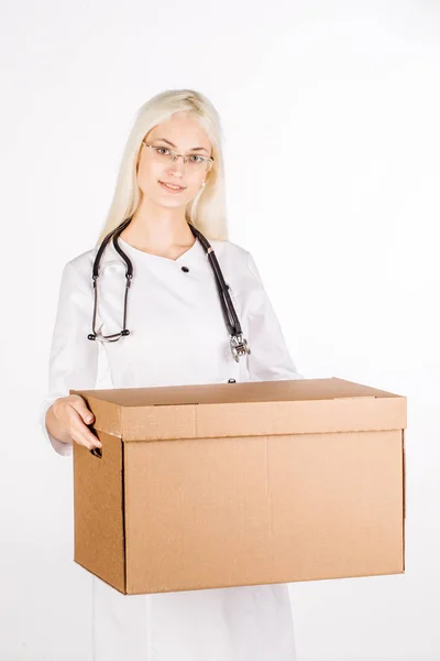Médico sorrindo, segurando caixa e olhando para a câmera — Fotografia de Stock