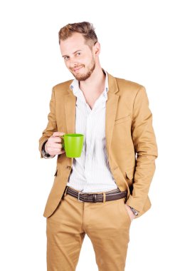 Emin yakışıklı delikanlı fincan sıcak bir içecek ile tutarak ve beyaz arka plan karşı dururken gülümseyen takım elbise
