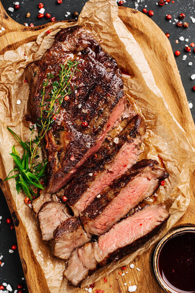 Juicy Beef rump steak from marble beef medium rare with sauce on wood plate, close-up. Selective focus.