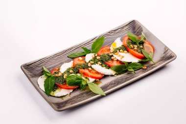 domates ve mozzarella peyniri dilimleri fesleğen yaprakları ile dekore edilmiştir. 
