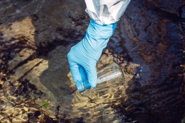 Eldiven elinde bir test tüpü içinde su toplar.