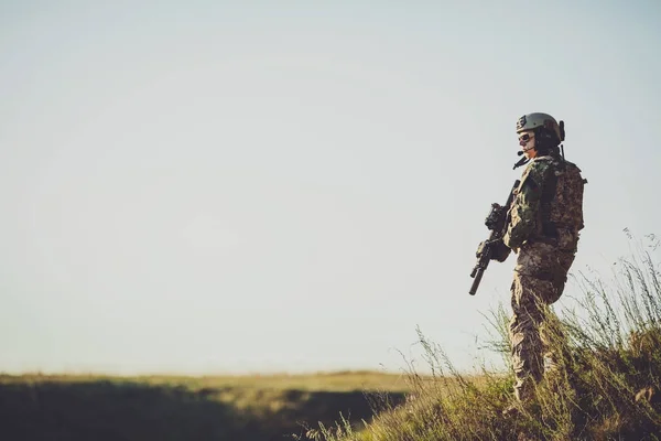 Voják se zbraní při západu slunce. trefa, drží zbraň, colo — Stock fotografie