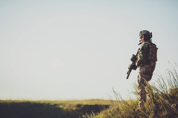 военный солдат с оружием на закате. выстрел, держа пистолет, коло
