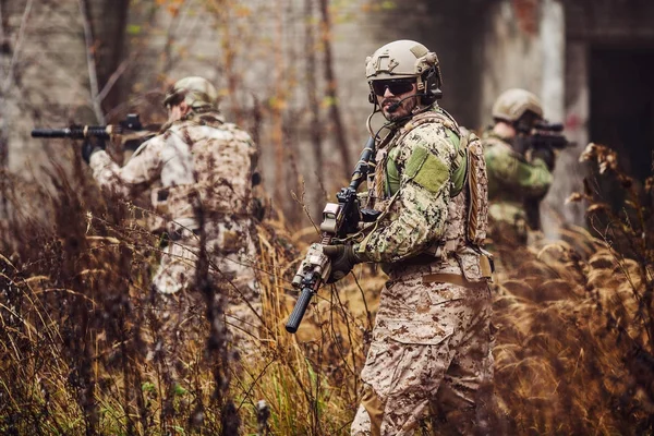 フル装備でライフルを持った兵士。背景に軍人 — ストック写真