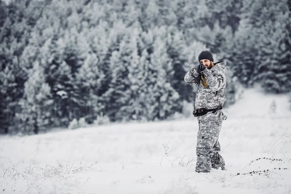 Male hunter in camouflage looking for his target or prey .Winter Stock Photo