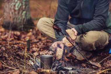 Elleri kırma ve ekmek kızartma bir avcı. Bushcraft kavramı