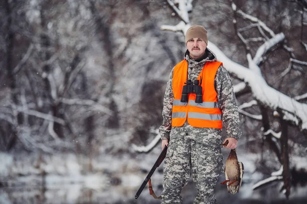 Caçador masculino em camuflagem, armado com uma espingarda, de pé em um sno — Fotografia de Stock