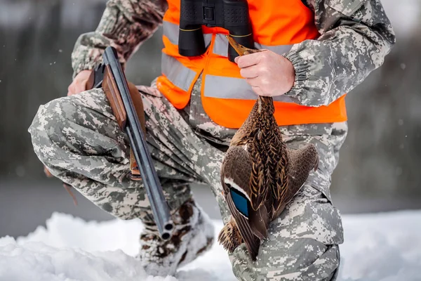 Manliga jägaren i kamouflage, beväpnad med ett gevär, stående i en sno — Stockfoto