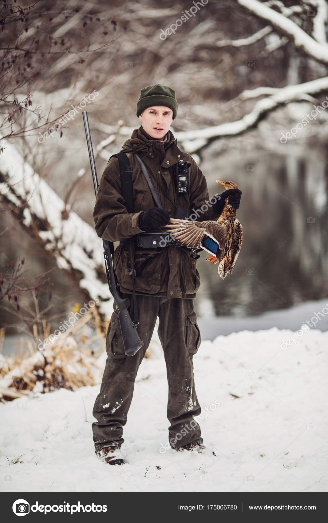 Male hunter in camouflage, armed with a rifle, standing in a sno