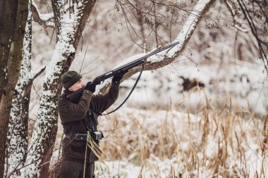 Kamuflaj, erkek avcısı silahlı bir tüfekle bir sno ayakta