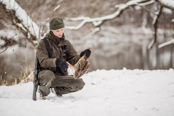 Kamuflaj, erkek avcısı silahlı bir tüfekle bir sno ayakta