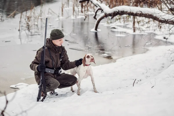 Caçador e seu Bourbonnais Apontando cão por um rio no inverno — Fotografia de Stock