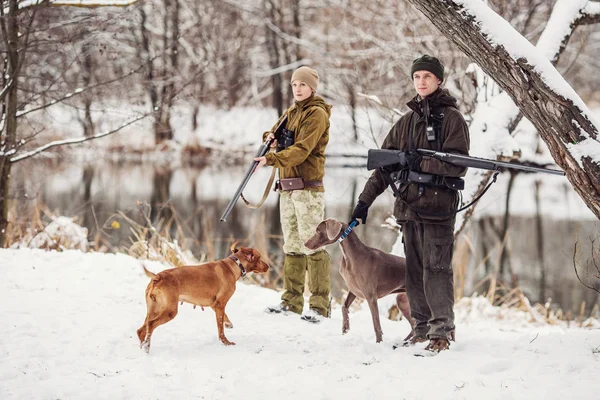 Två jägare med gevär i en snöig vinter skog. — Stockfoto